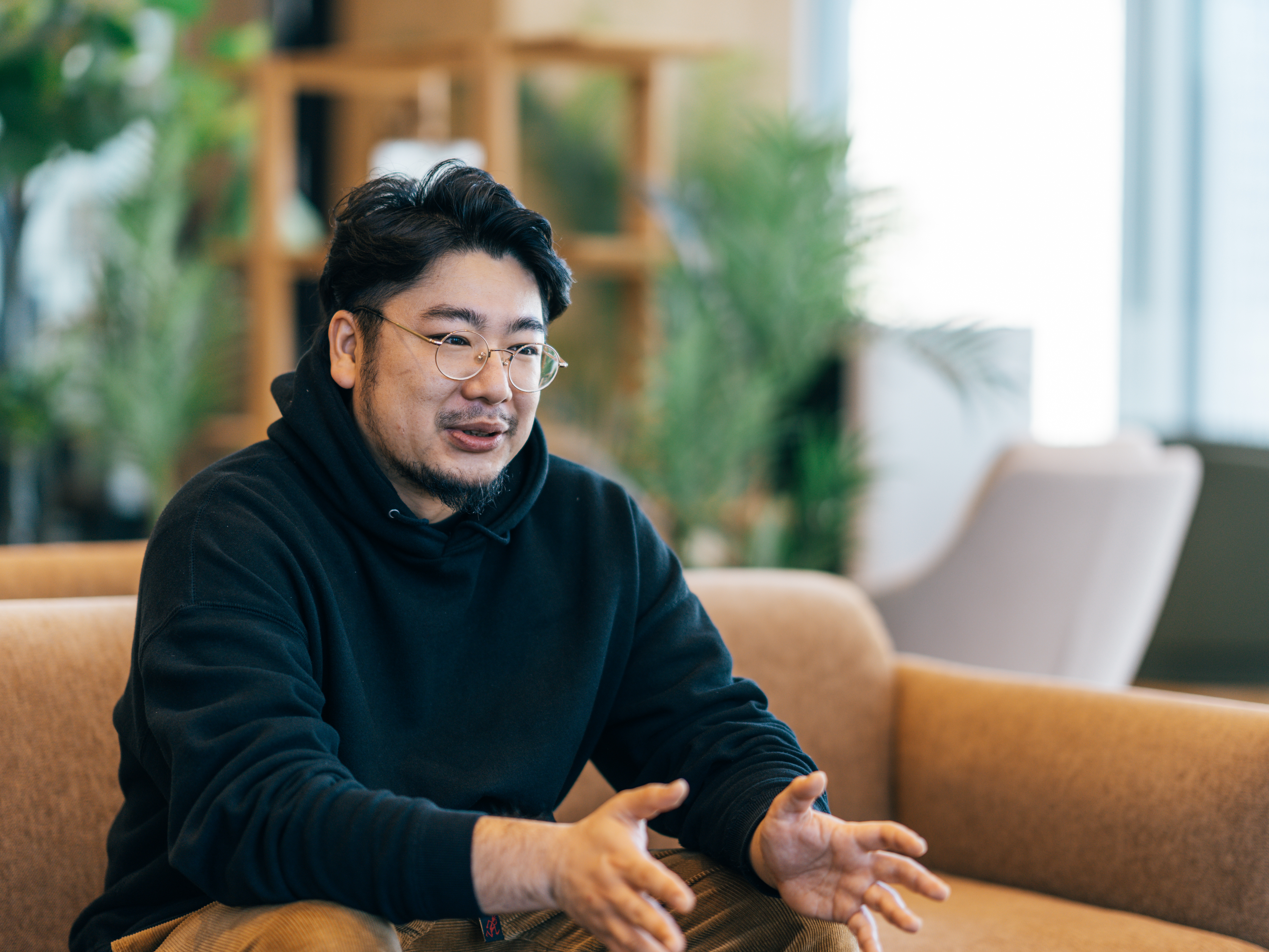 Shuhei Ishikawa talks while sitting on the sofa in the office